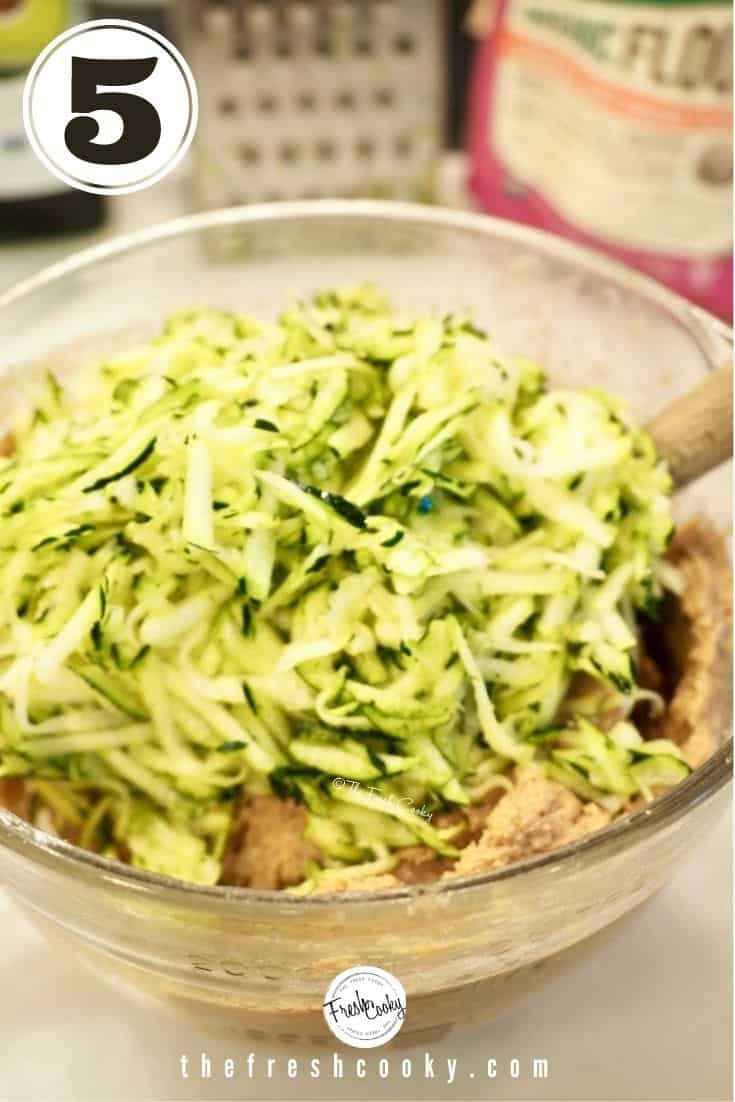 grated zucchini in mixing bowl with zucchini bread batter