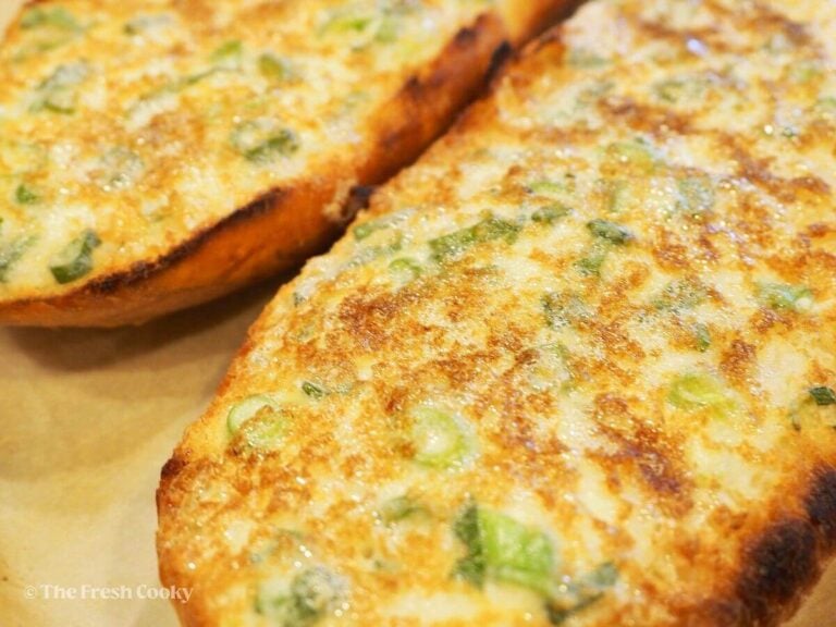Halves of cheesy garlic bread just out of the oven, golden brown.