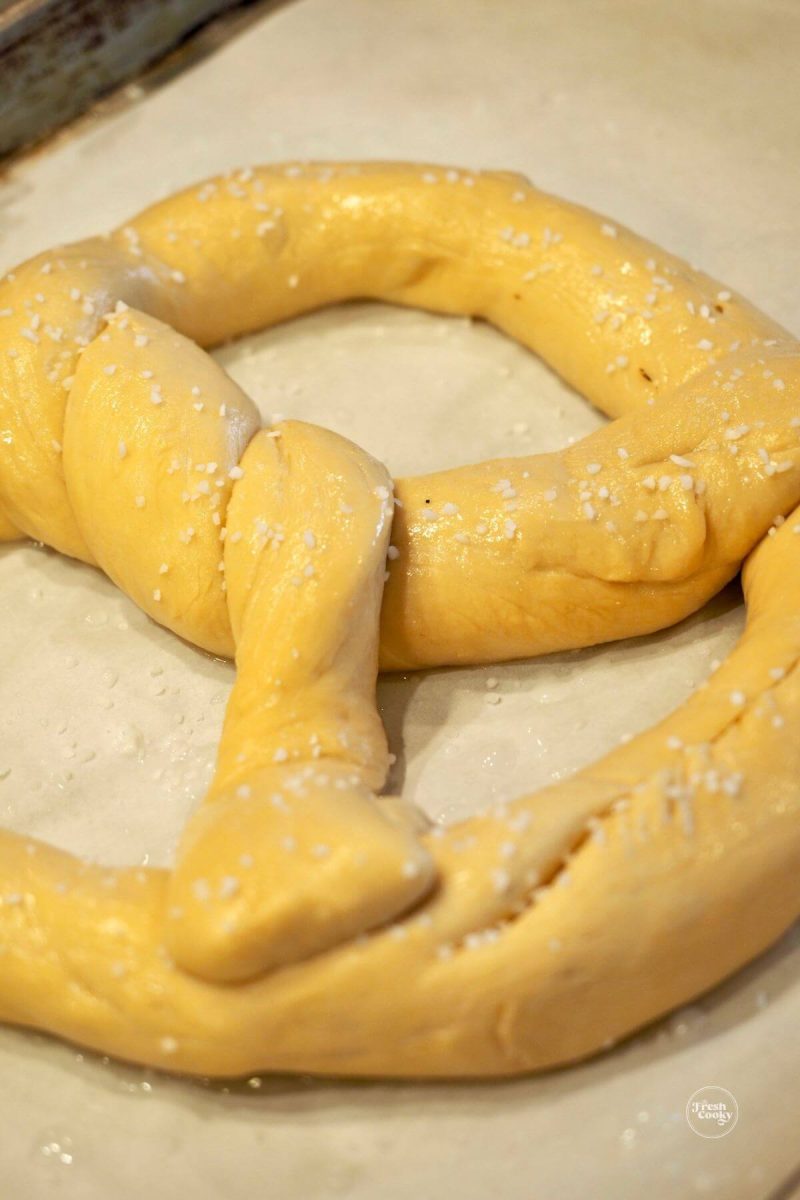 Risen German pretzel brushed with baking soda water and sprinkled with pretzel salt.
