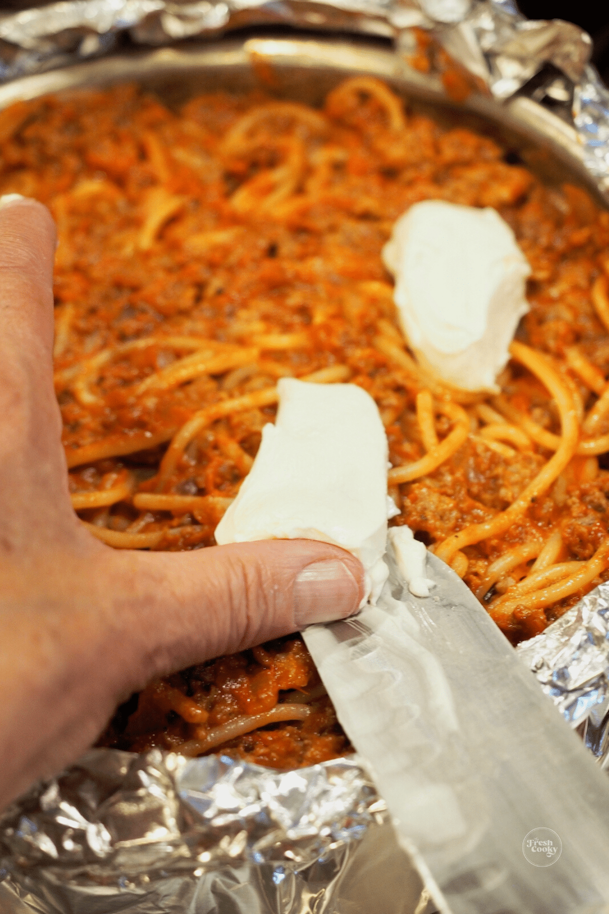 Add layers of cheese to spaghetti pie.