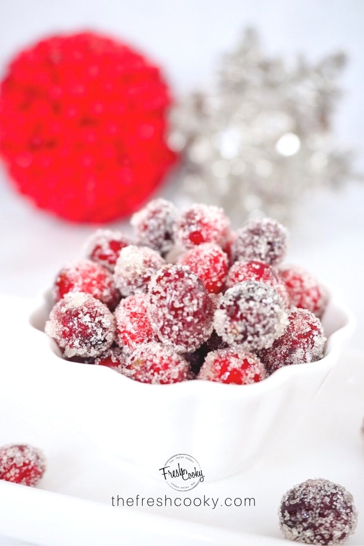 A bowl of sparkling sugared or candied cranberries with Christmas decor in background | thefreshcooky.com