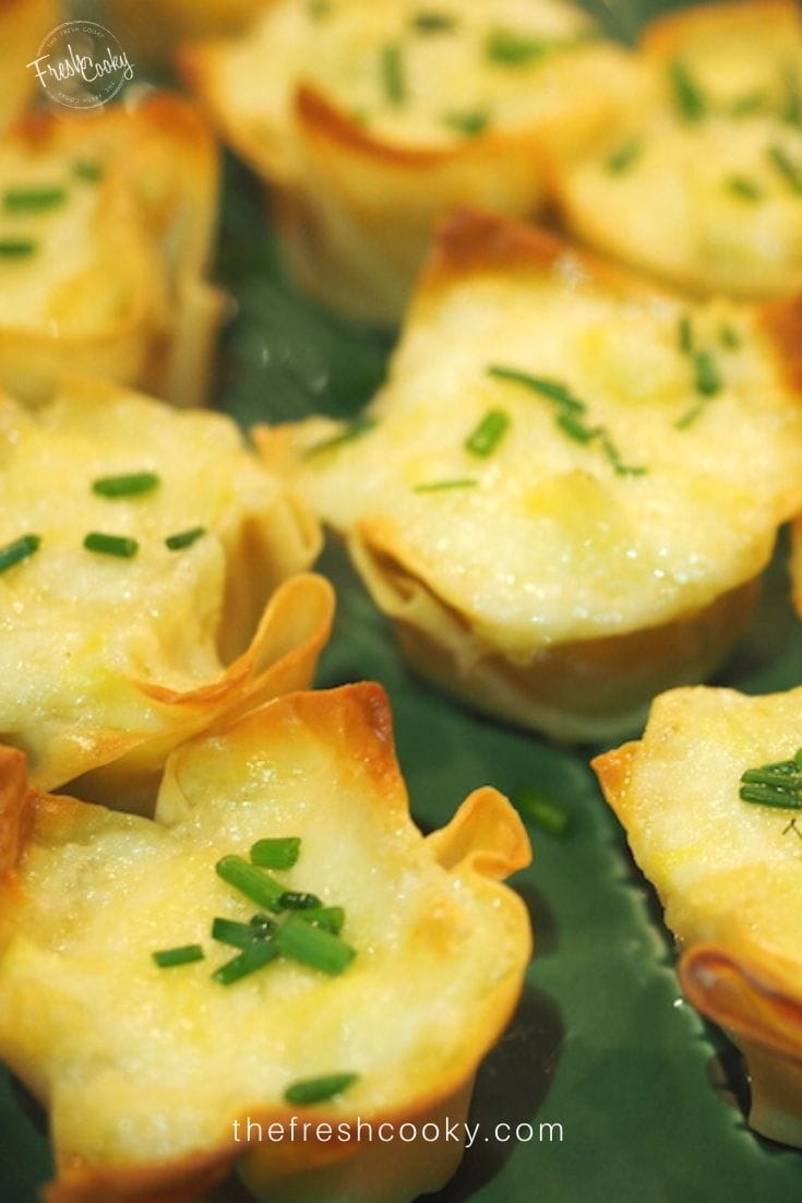 Close up shot of artichoke cheese wontons baked and sitting on a green ceramic platter.