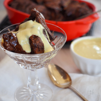 Chocolate bread and butter pudding with serving of pudding in crystal glass drizzled with creme anglaise sauce.