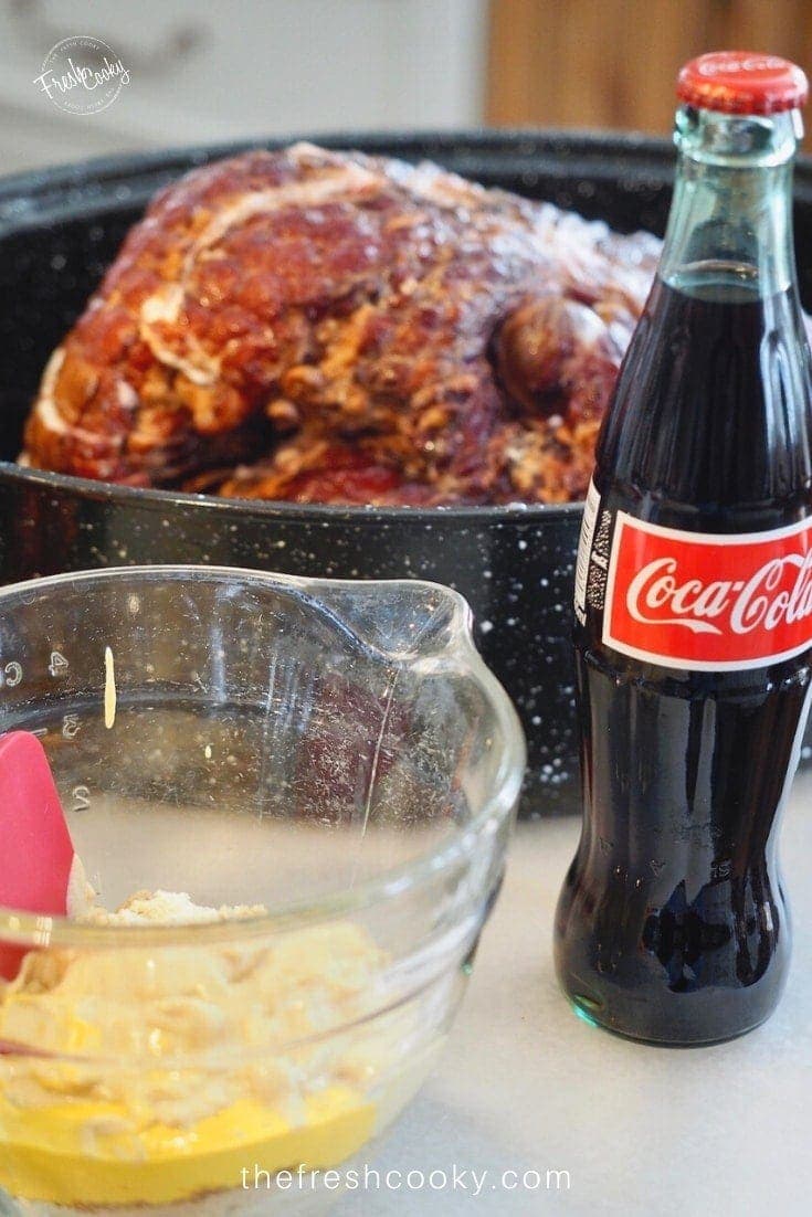 Image of whole ham in roasting pan, brown sugar, dijon mustard glaze ingredients with bottle of Mexican Coca Cola in front.