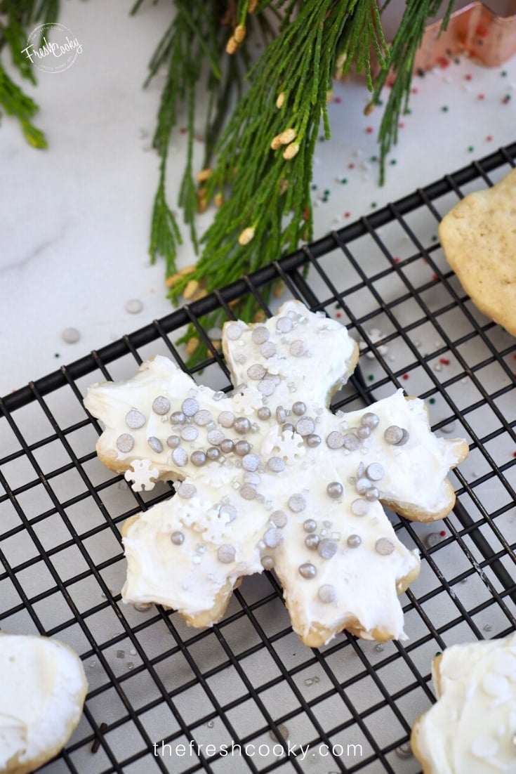 Snowflake cut out cookie, frosted and covered in silver sprinkles.