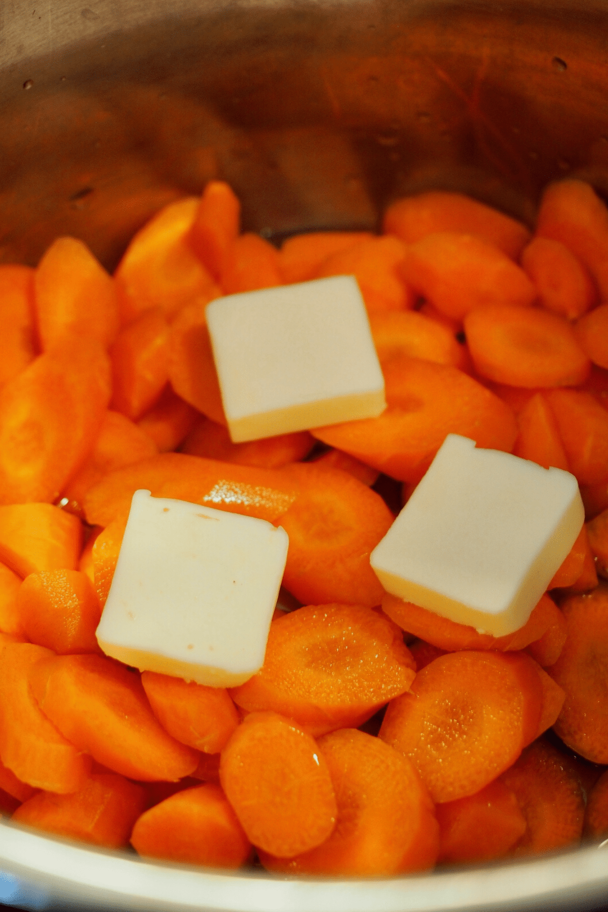 Carrots in instant pot with butter pats and water. 