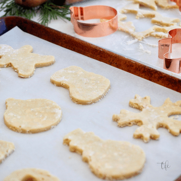 Rolled Oatmeal Sugar Cookies, with cut out cookies on sheet pan and copper cookie cutters in background.