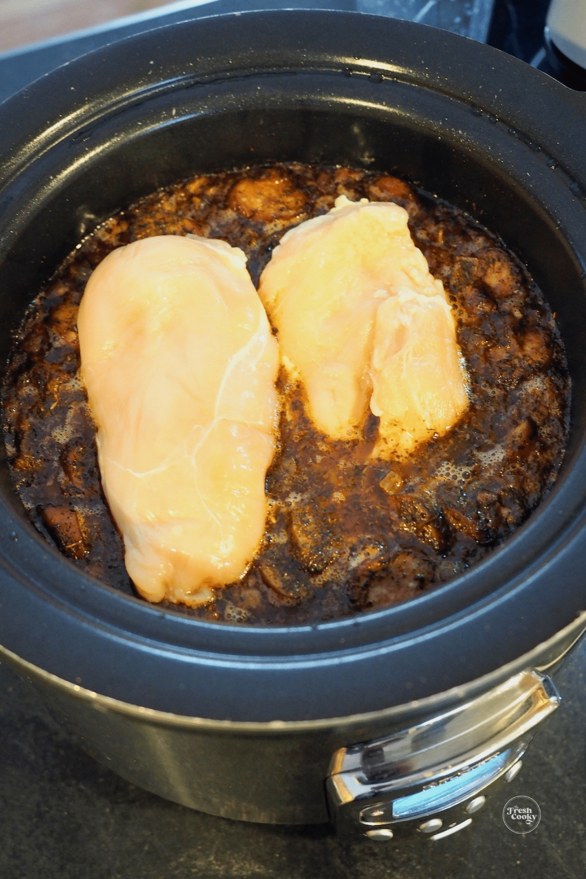 Add chicken breasts to slow cooker a few hours before it's ready to serve.