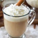 Mug filled with creamy hot buttered rum topped with whipped cream and a cinnamon stick.