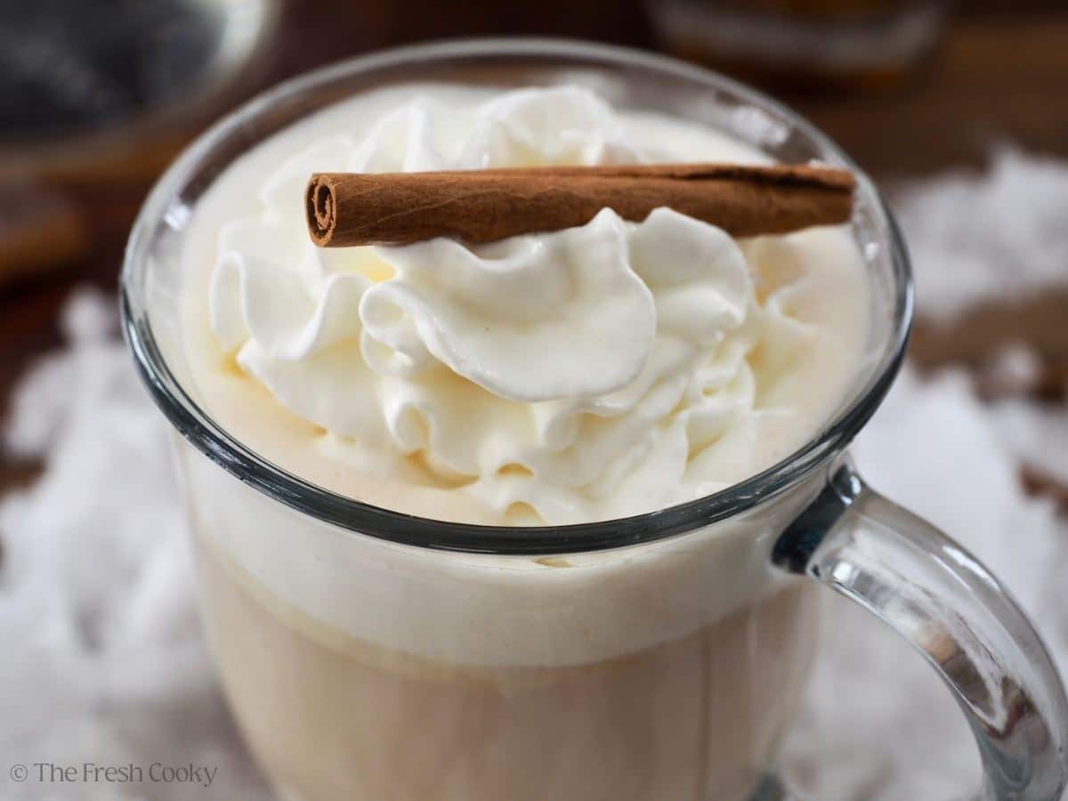 Close up of mug with hot buttered rum topped wit whipped cream.