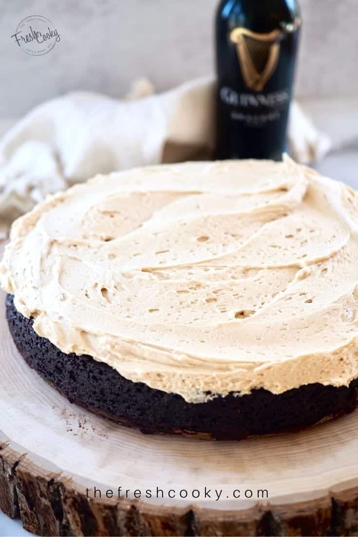 high altitude Chocolate Guinness Cake with Irish Buttercream frosting on a slice of wood with a bottle of Guinness in the background