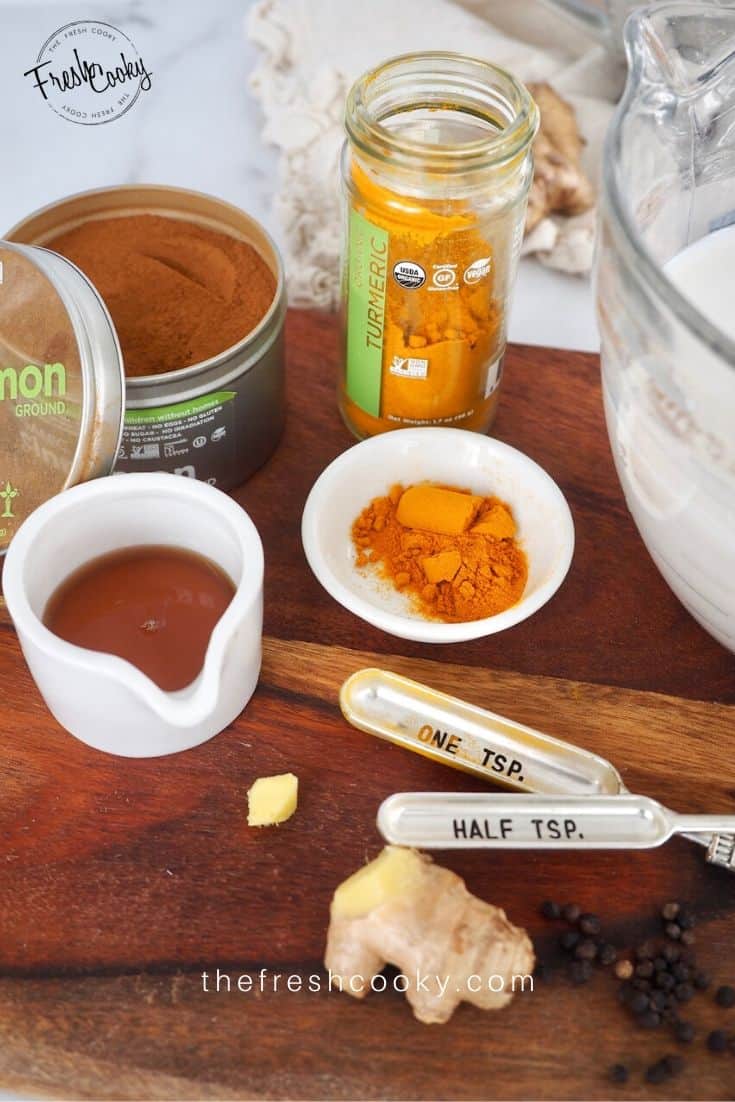 Ingredients for Golden Milk Turmeric Tea on wooden cutting board. 