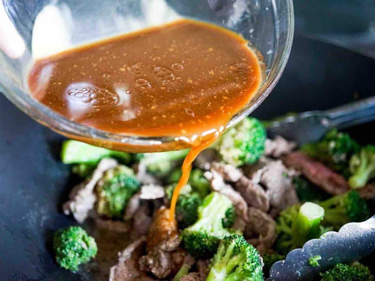 Pouring sauce into beef and broccoli stir fry.