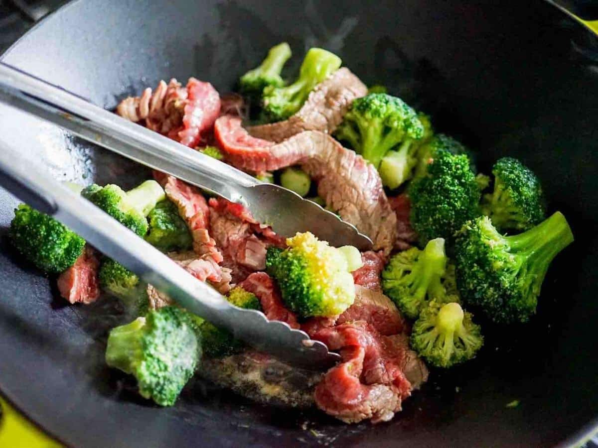 Stir frying beef and broccoli in a wok.