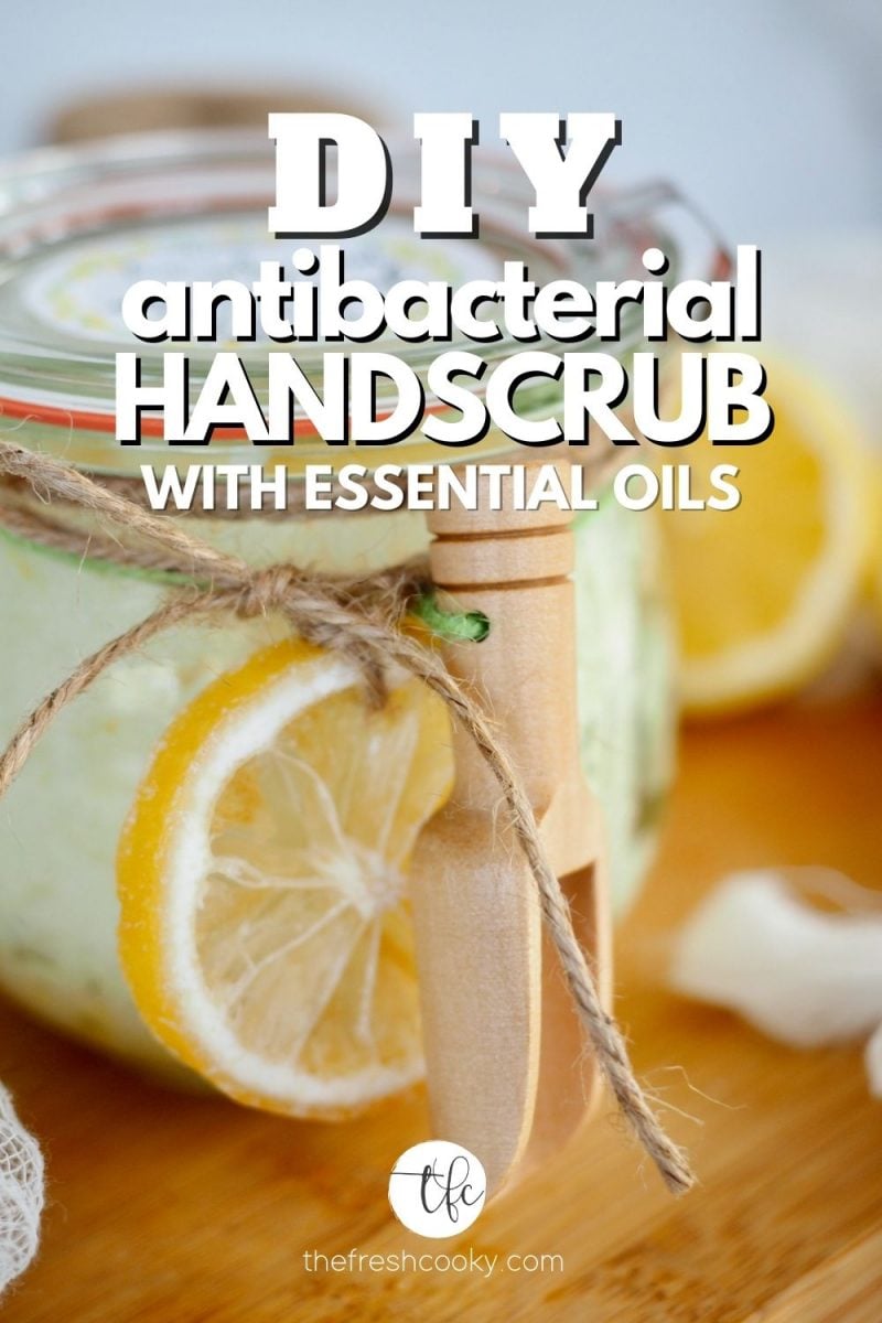 DIY antibacterial Hand Scrub with essential oils with image of glass jar filled with hand scrub and tied with twine and a dried lemon and wood scoop.