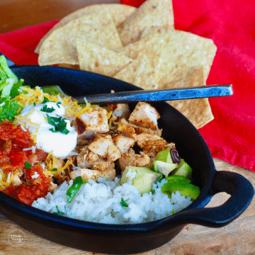 Copycat chipotle chicken burrito bowl with chips in a cast iron pan.