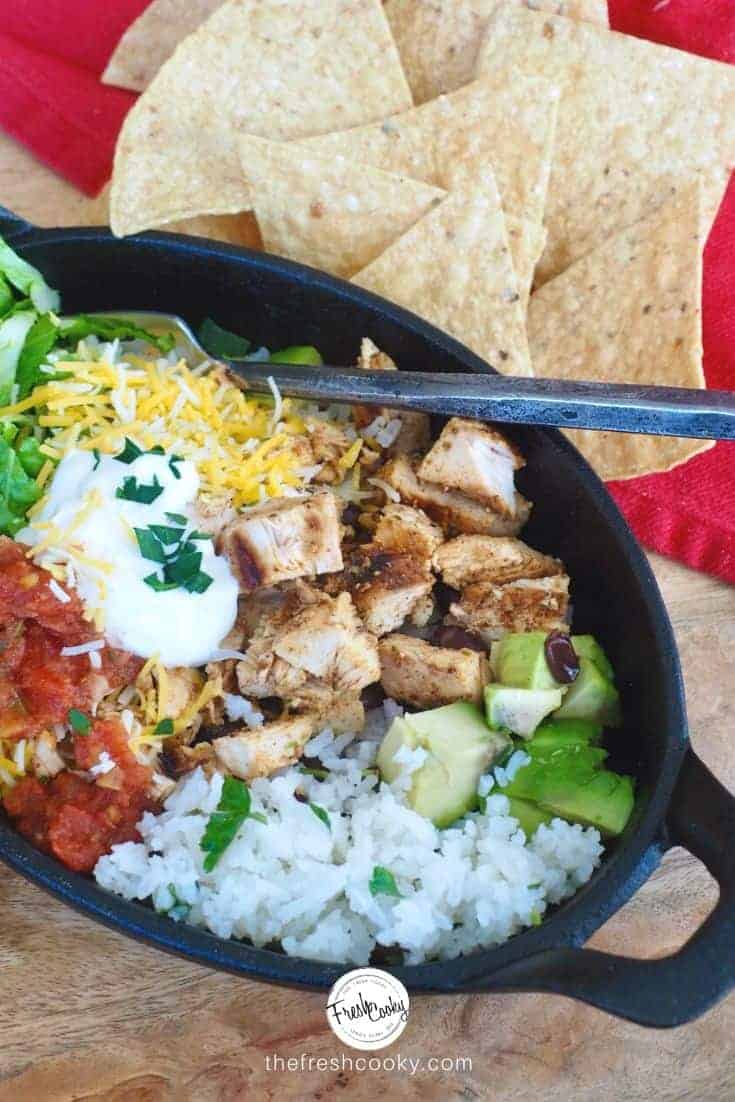 Copycat Chicken Burrito bowl in cast iron pan with cilantro lime rice and all the toppings. 