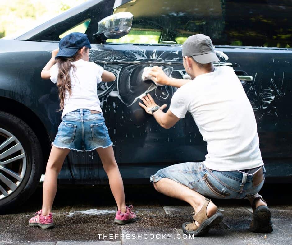 A dad and daughter washing the family car. 