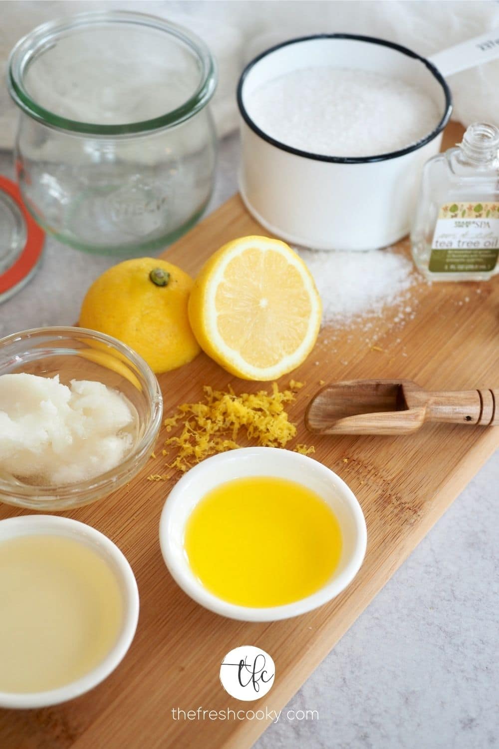 Anitbacterial Handscrub on wooden cutting board ingredients. Kosher Salt, Fresh Lemon, Jojoba Oil, Coconut Oil, Sweet Almond Oil, Esseintial Oils.