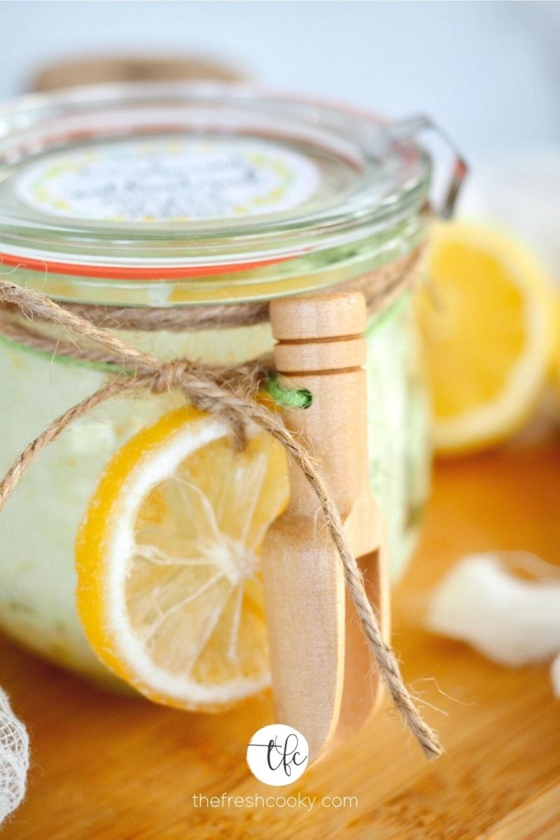 Beautiful glass weck jar filled with lemon antibacterial hand scrub with dried lemon and wooden scoop tied on for presentation with free printable label. 