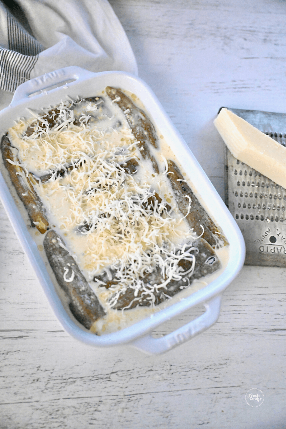 Extra grated cheese on chile relleno casserole ready for oven. 