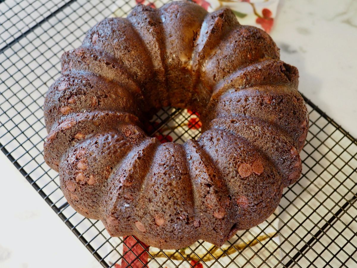 Full sized chocolate chocolate chip bundt cake on cooling rack. 