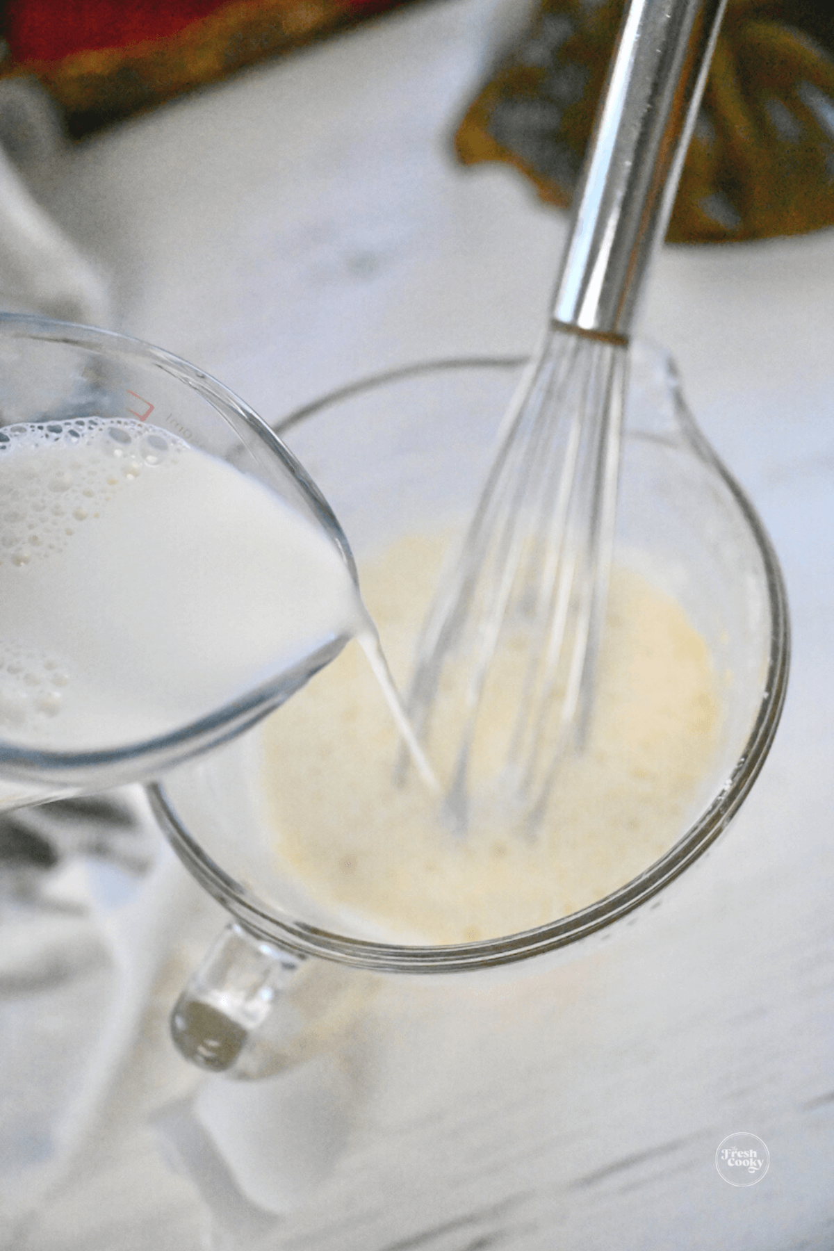 Pouring milk into flour, salt and egg batter. 