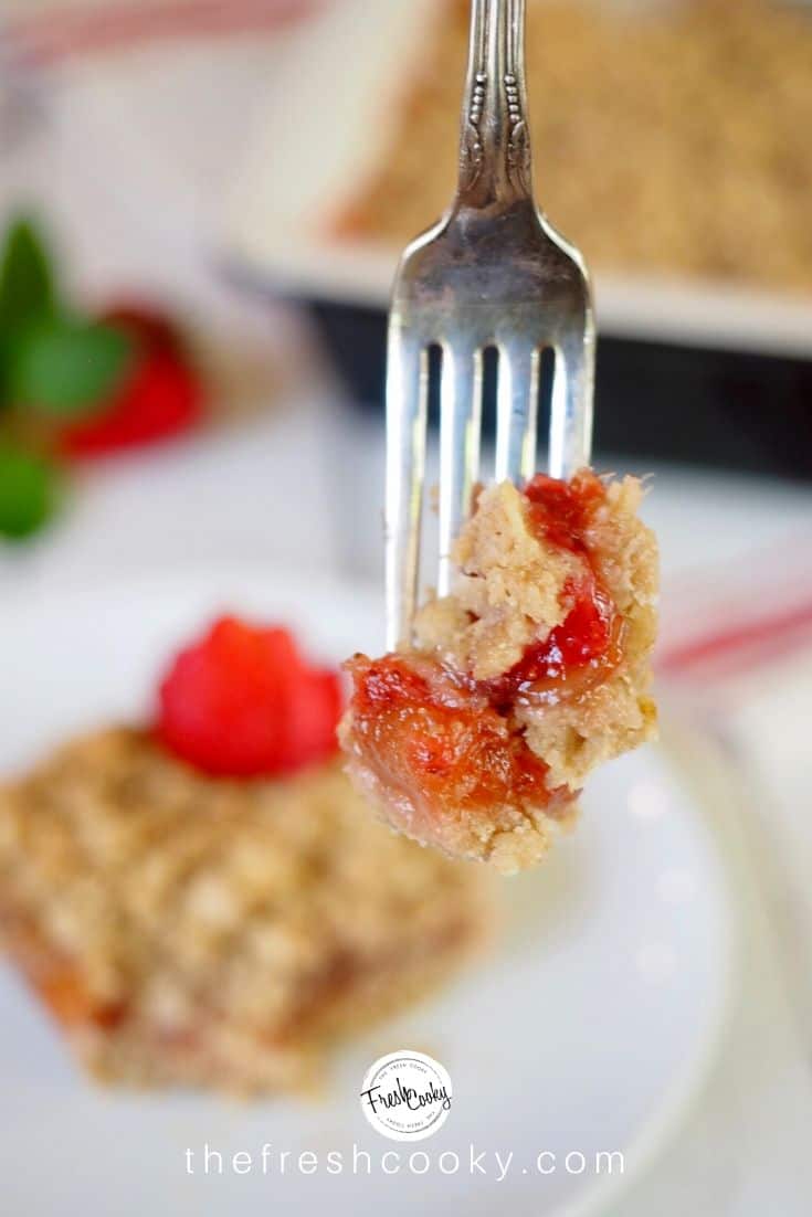 Fork with bite of moist strawberry rhubarb crumb oat bars. 