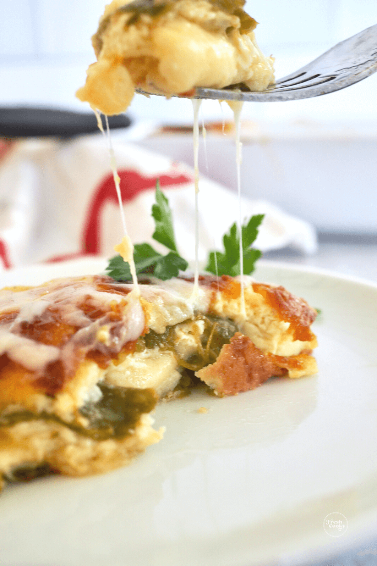 Easy chile relleno casserole slice on plate with bite of cheesey chile relleno on fork.