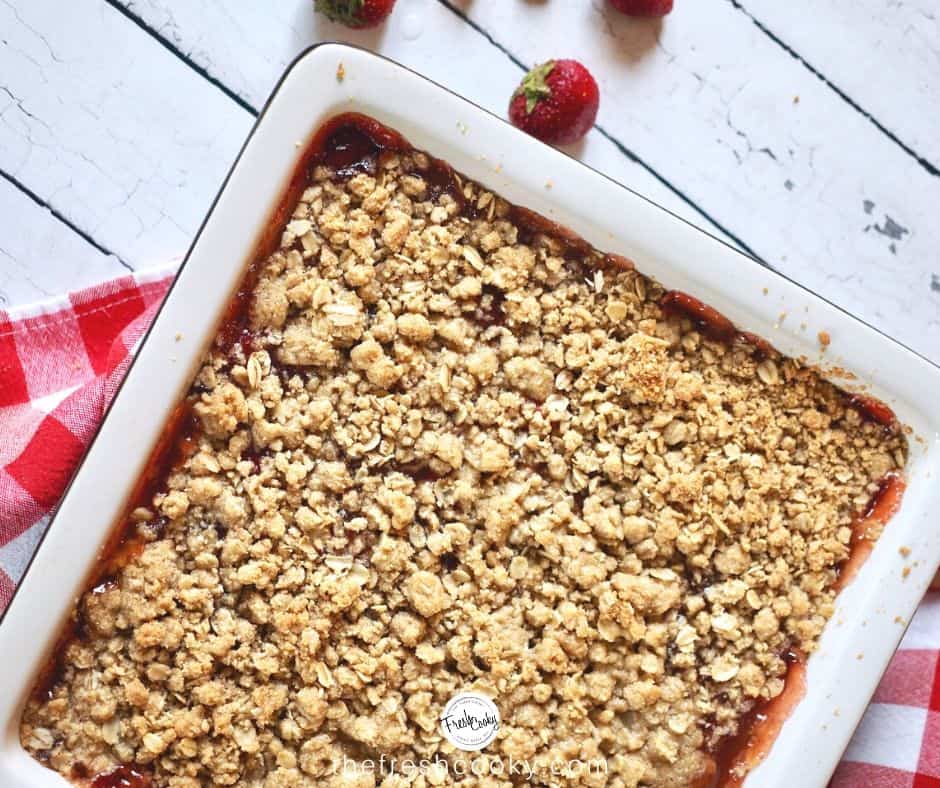 Facebook image for strawberry rhubarb crumb bars in pan with red checked napkin. 