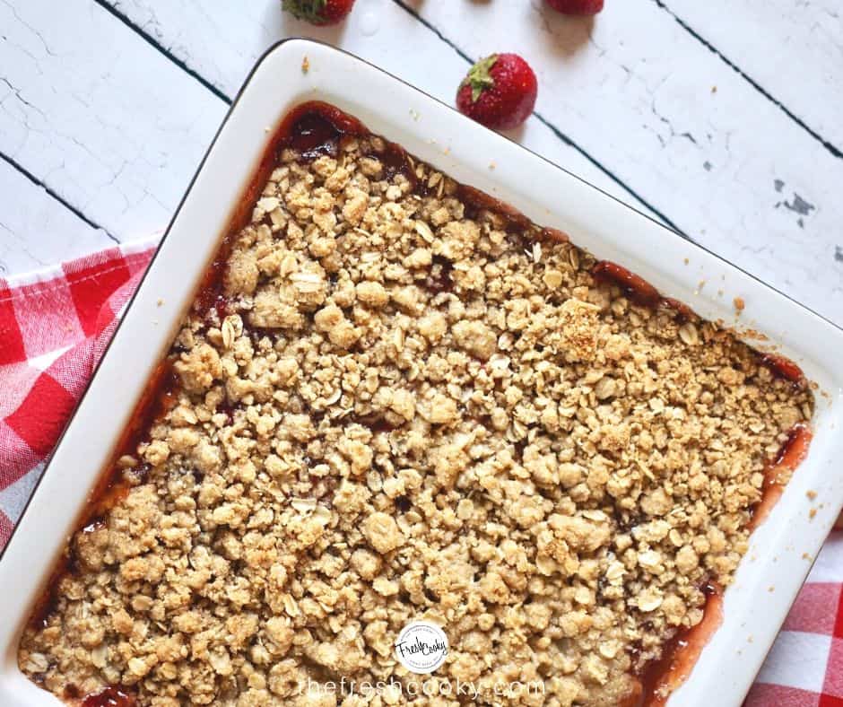 Facebook image for strawberry rhubarb crumb bars in pan with red checked napkin.