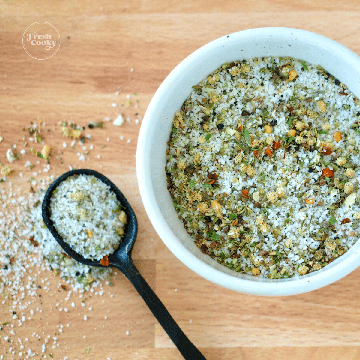 Square image of Carrabba's Grill Seasoning mix with spoon on table and seasoning in bowl.