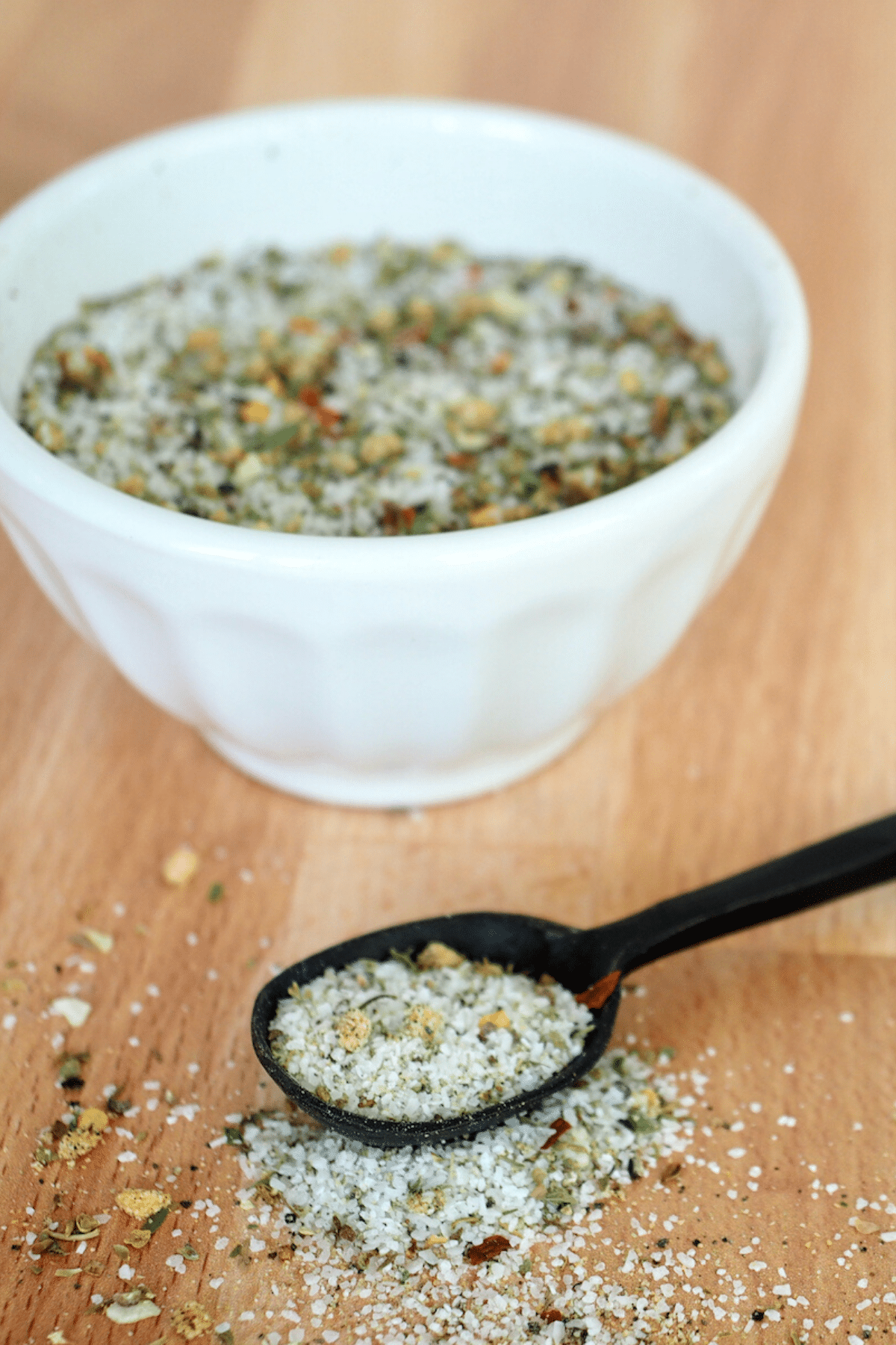 Image of bowl filled with Carrabba's grill seasoning with black spoon in front filled with seasoning.