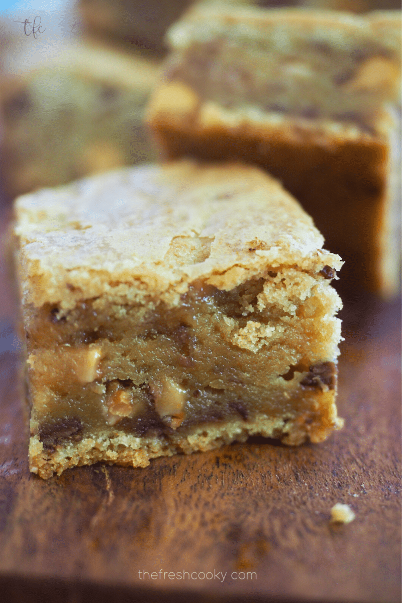 Chewy Blondie recipe with english toffee Heath bits and butterscotch chips on a wooden tray.