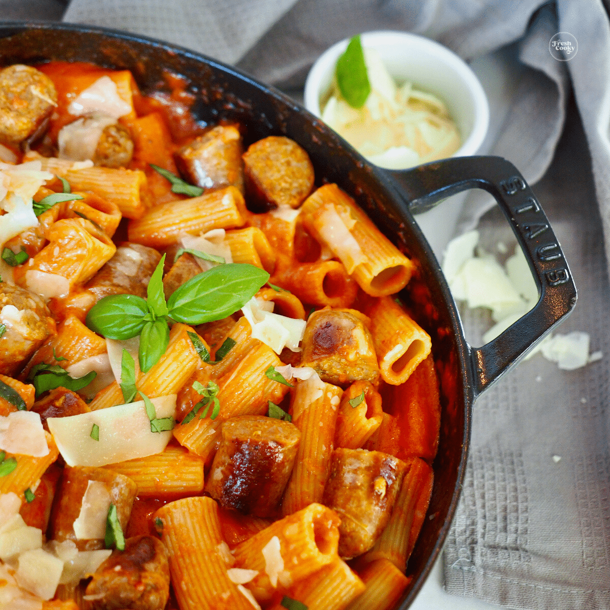 Penne alla vodka in cast iron skillet garnished with fresh basil and parmesan shavings.