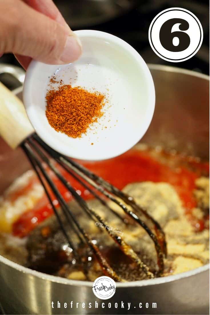 small white bowl with cayenne pepper going into sauce mixture.