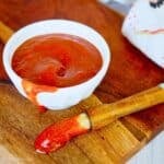 Homemade barbecue sauce in a cup with a basting brush.