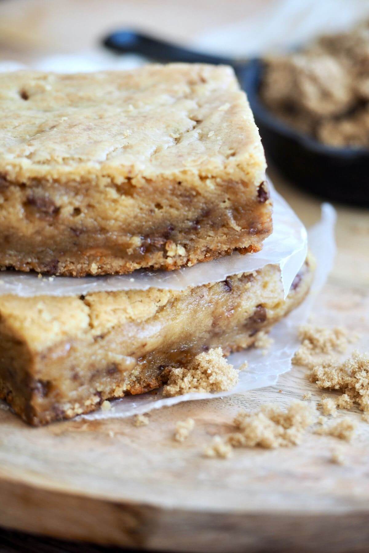 Two blondies with mix-ins stacked on top of each other with parchment between. 