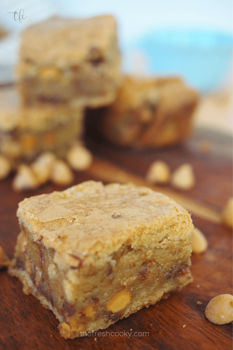 Chewy Blondies on a cutting board with butterscotch chips sprinkled around.