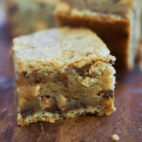 Square Image for best chewy blondies recipe with blondie sitting gooey and thick on a cutting board.