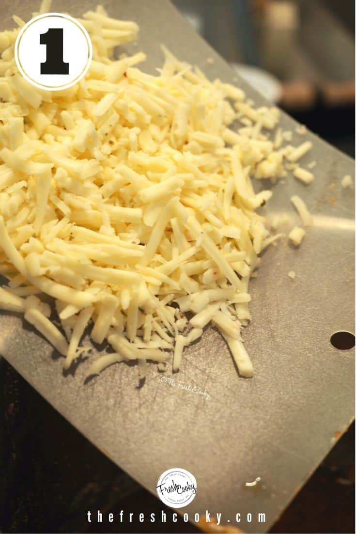 Shredded pepper jack cheese on flexible cutting board going into Instant Pot