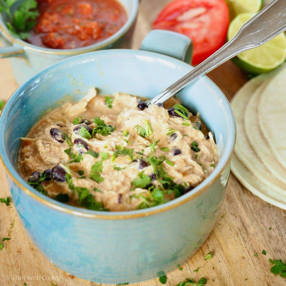 Salsa and cream cheese chicken in a ceramic bowl ready to make tacos.