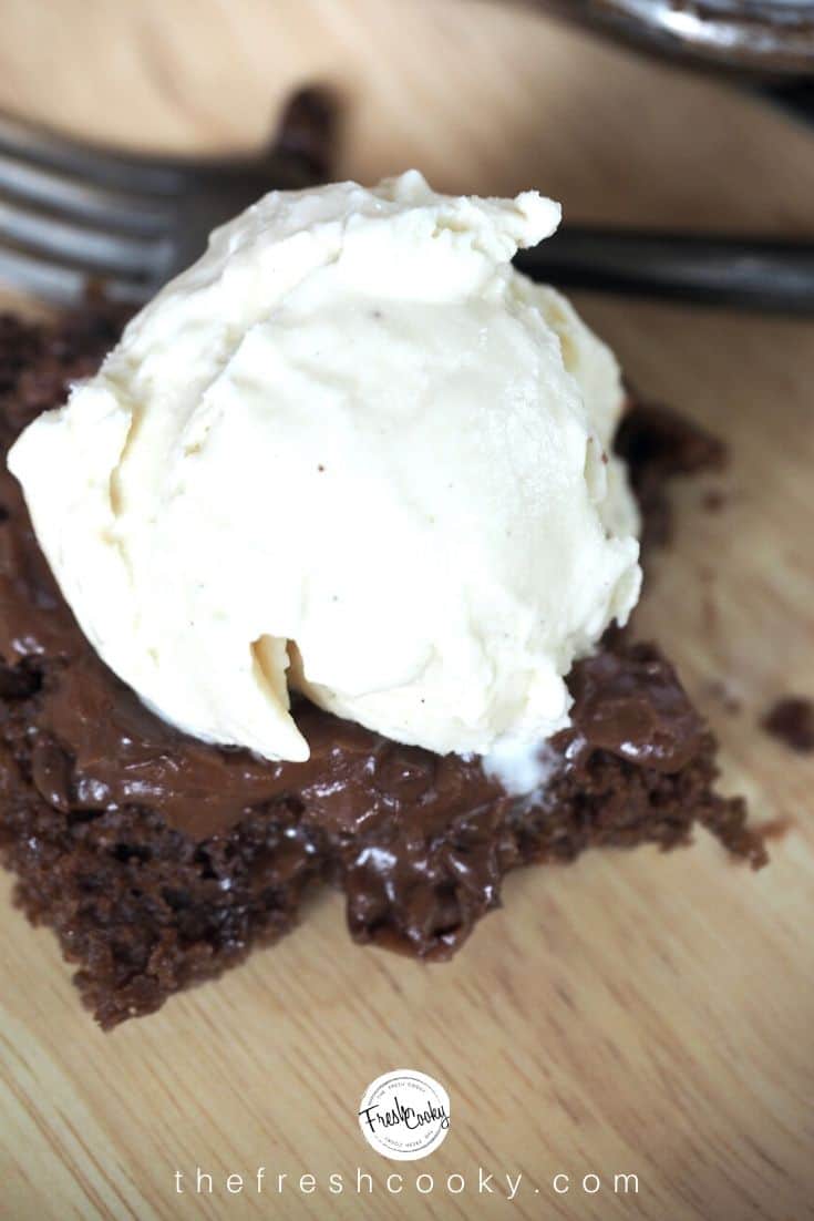 Close up shot of a square of the Best Texas Sheet Cake, warm with melting vanilla ice cream on top on a bamboo plate