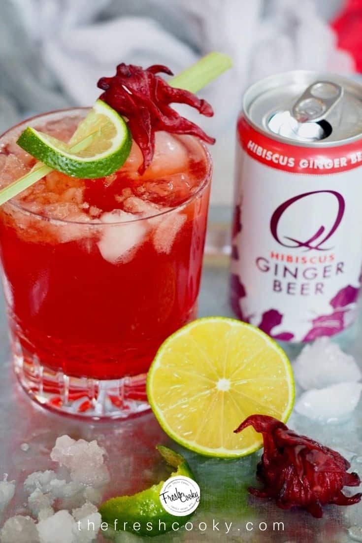 Shot of Red cocktail in crystal glass, a Dark & Stormy cocktail with a can of Q Mixers Hibiscus Ginger Beer a lime and ice. 