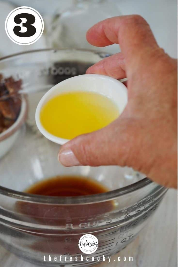 Hand pouring small white bowl with melted butter into glass mixing bowl