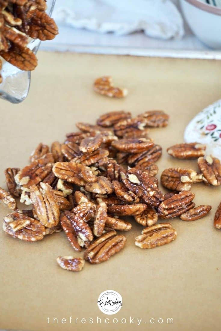 pouring pecan halves onto parchment lined baking sheet that have been mixed with slurry.