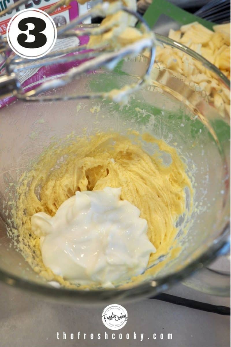 glass mixing bowl with creamed butter and sugar with added greek yogurt to bowl