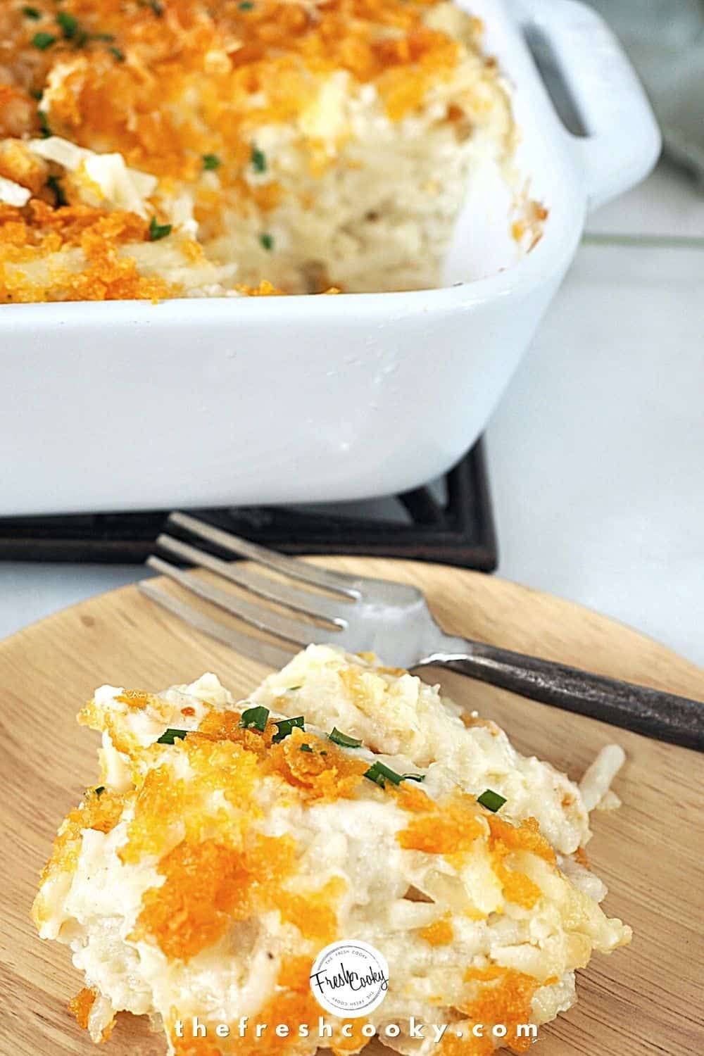 Scoop of cheesy potato casserole on plate with fork. 