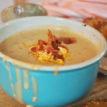 Beer and Cheese soup in turquoise bowl with bacon and cheese, square image.