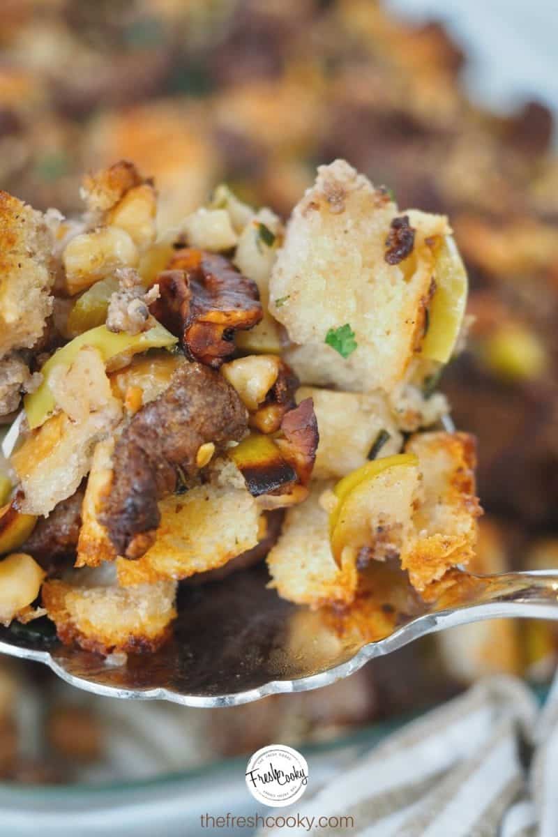 Large spoonful of the best Thanksgiving stuffing with the casserole in the background.